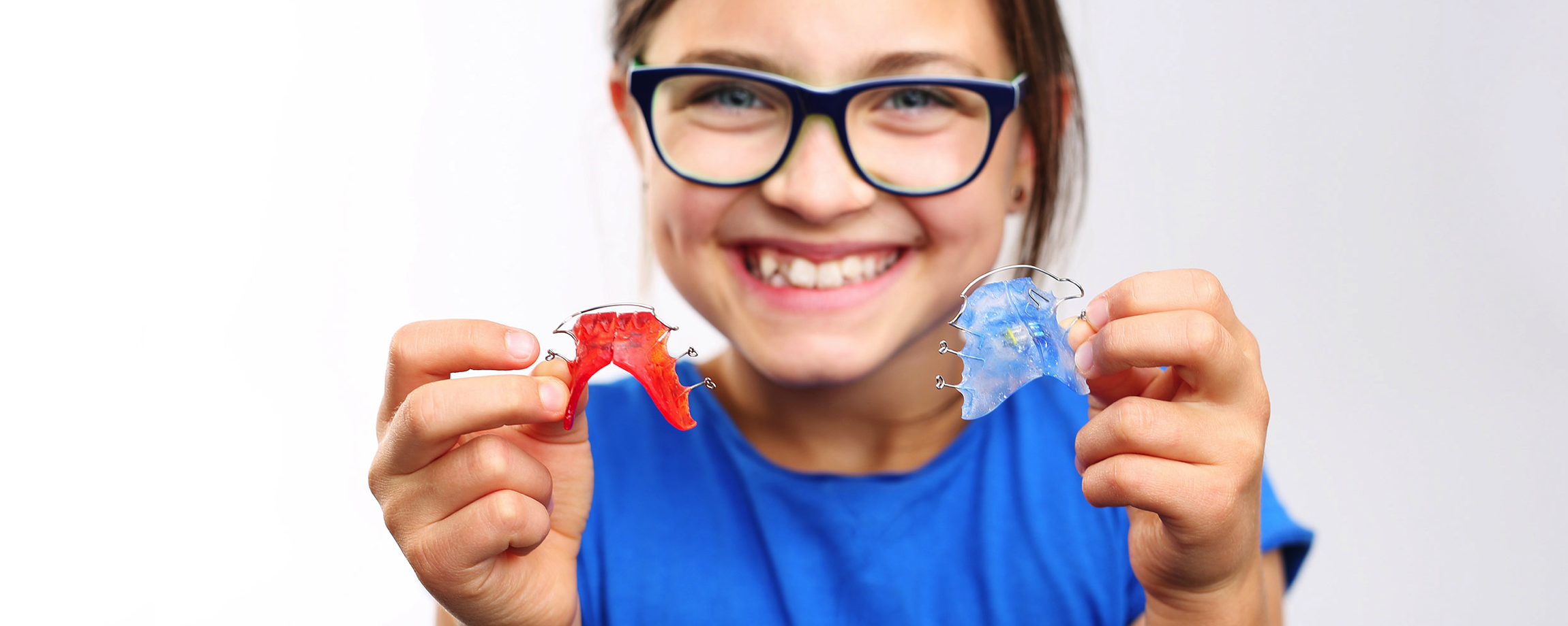 Fetiță zâmbind cu un aparat dentar în mână